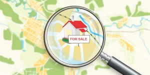 An illustrated map with a magnifying glass zooming in on a house labeled "For Sale," representing Miami County property search.