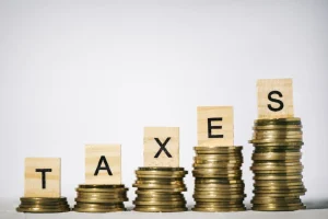 Stacked coins with wooden blocks spelling the word 'taxes,' representing financial planning for Miami Dade County real estate taxes.